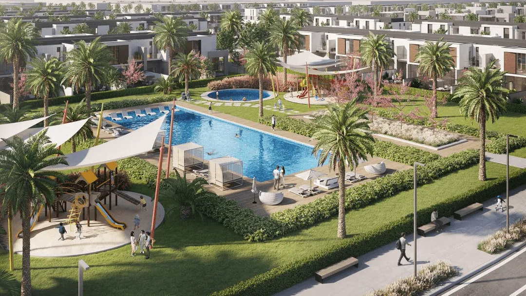Modern residential community with palm trees, a large swimming pool, playground, and people walking and relaxing outdoors.