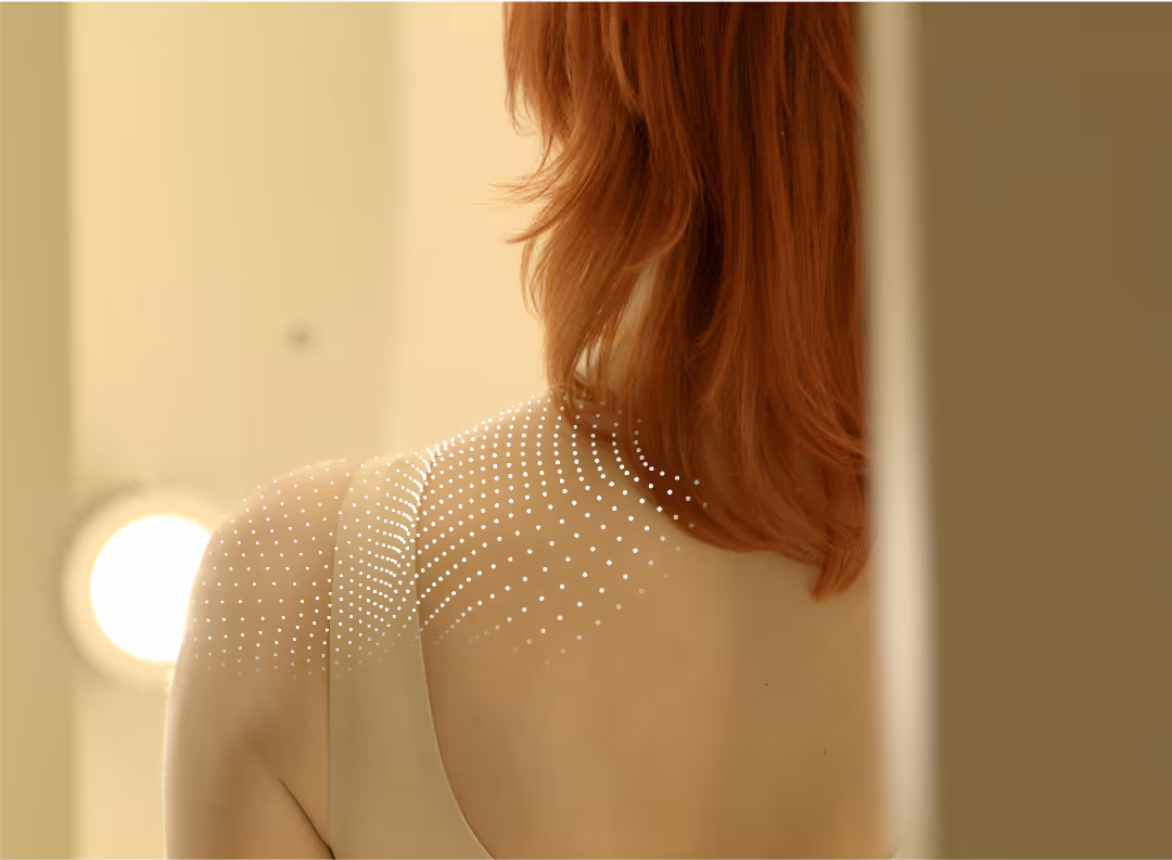 Back of a person with red hair wearing a sleeveless top and white dotted graphic on their shoulder.