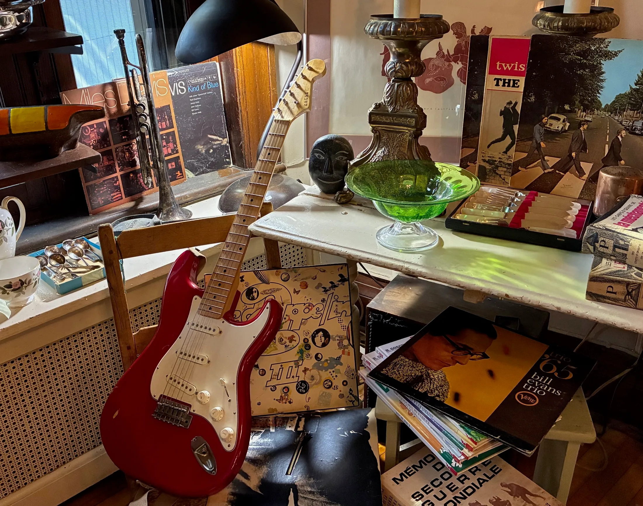 Guitare électrique rouge, disques vinyles et objets vintage lors d'une vente de déménagement