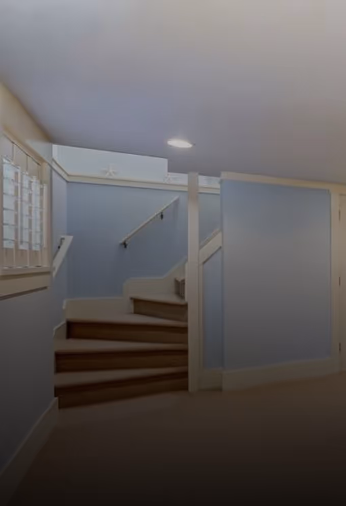 Indoor staircase with beige steps and blue walls illuminated by ceiling light.