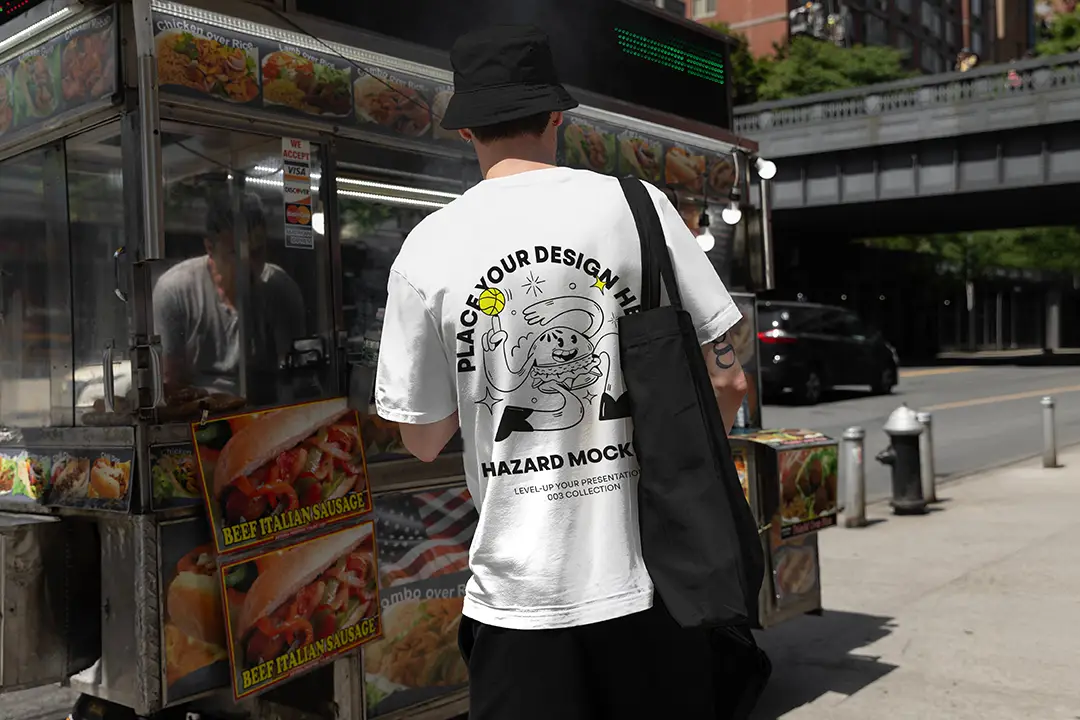 Showcase your designs with this NYC streetwear mockup featuring a model in front of a hotdog stand. Customize the t-shirt and tote bag in any color to bring your branding to life! Ideal for apparel and accessory brands.