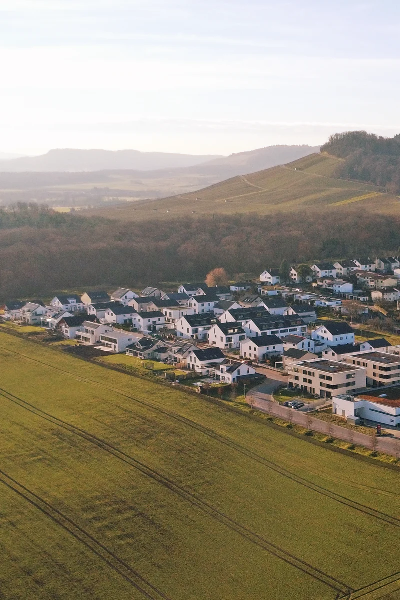 Luftaufnahme von Freudental: Neubaugebiet am Ortsrand mit Einfamilienhäusern, Feldern und Weinbergen im Hintergrund.