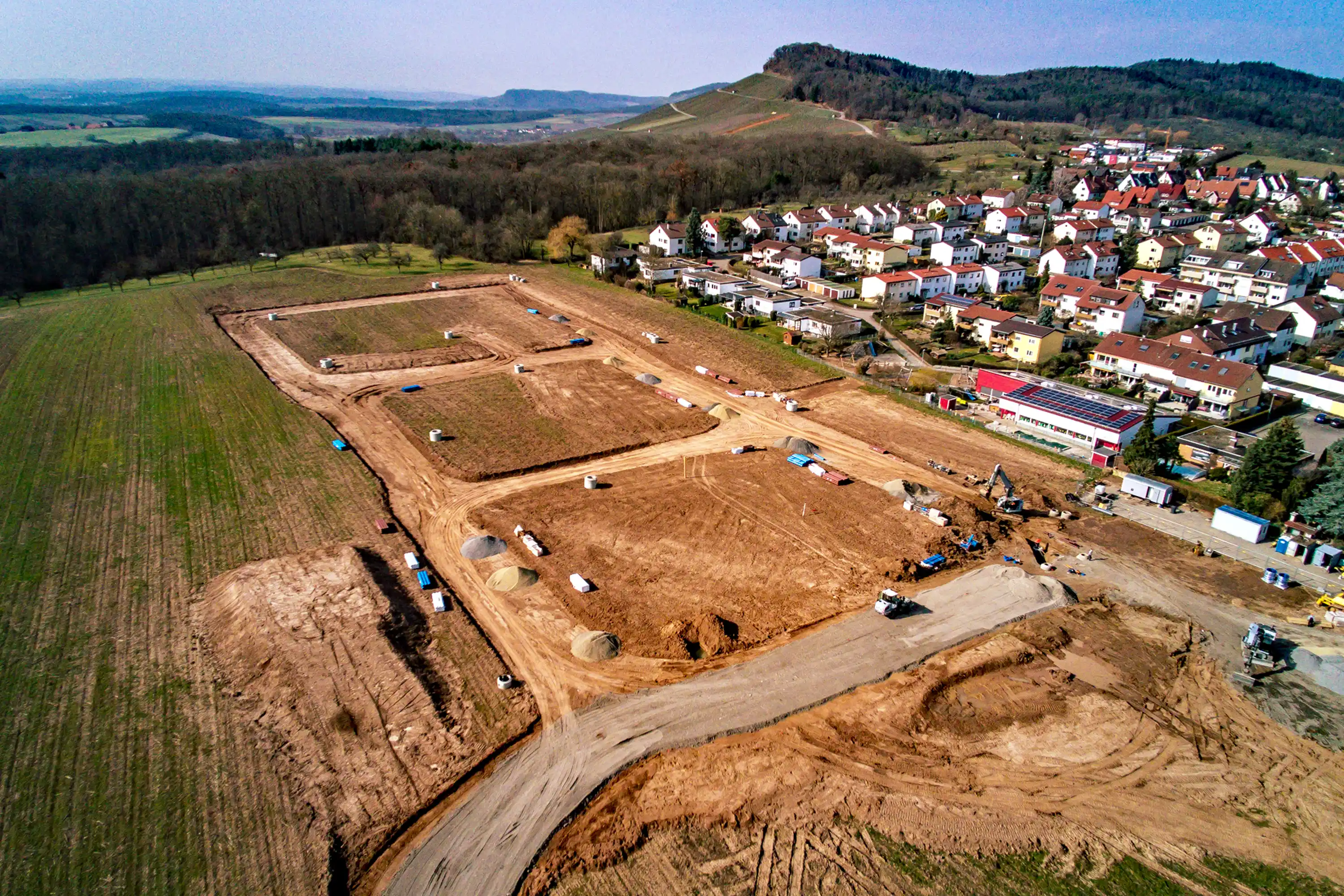 Baugebiet in Freudental im Rohzustand: Erschließungsstraßen, Parzellen und Erdarbeiten neben bestehender Wohnbebauung.
