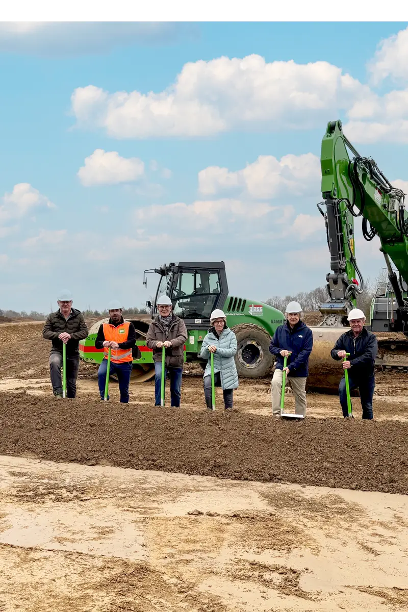 Sechs Personen auf einem Acker, im Hintergrund ein grüner Bagger. Gezeigt wird der Spatenstich der Personen Herr Kobold, Herr Costa (beide Fa. Glass-bau GmbH), BM Jautz, Frau Kästle (beide Gemeinde Warthausen), Herr Schwörer, Herr Vogel (beide IB Schwörer)