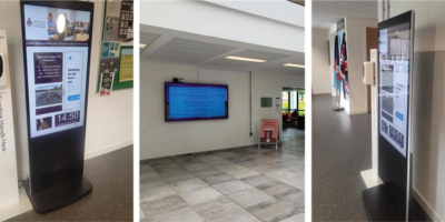 Three digital information displays in indoor public spaces, showing event and health info on screens.