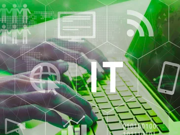 Hands typing on a laptop keyboard with IT text and digital technology icons overlay.