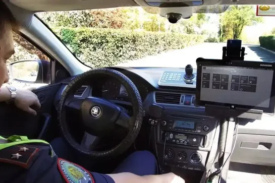 View of a police officer inside a car, showing the steering wheel and mounted police computer screen.