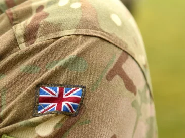Union Jack patch on the sleeve of a camouflaged military uniform.