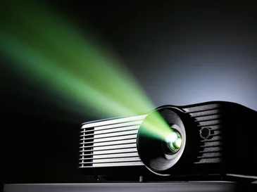 Black projector emitting a green beam of light in a dark environment.