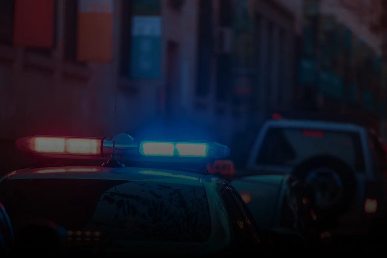 Police car with red and blue flashing lights on a dark street at night.