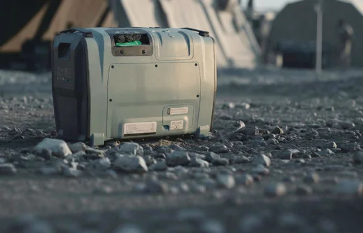 Portable power station resting on rocky ground outdoors near tents.