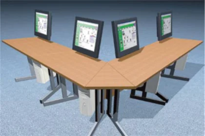 V-shaped wooden office desks with four computer monitors on gray carpeted floor.