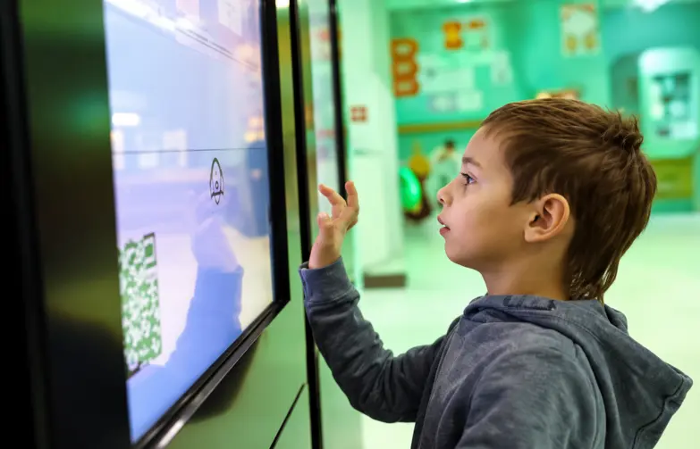 Viasat security solutions Young boy in a hoodie interacts with an interactive touch screen