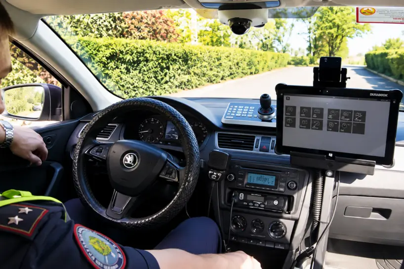 Operational technology expertise View of a police officer inside a car, showing the steering wheel and mounted police computer screen.