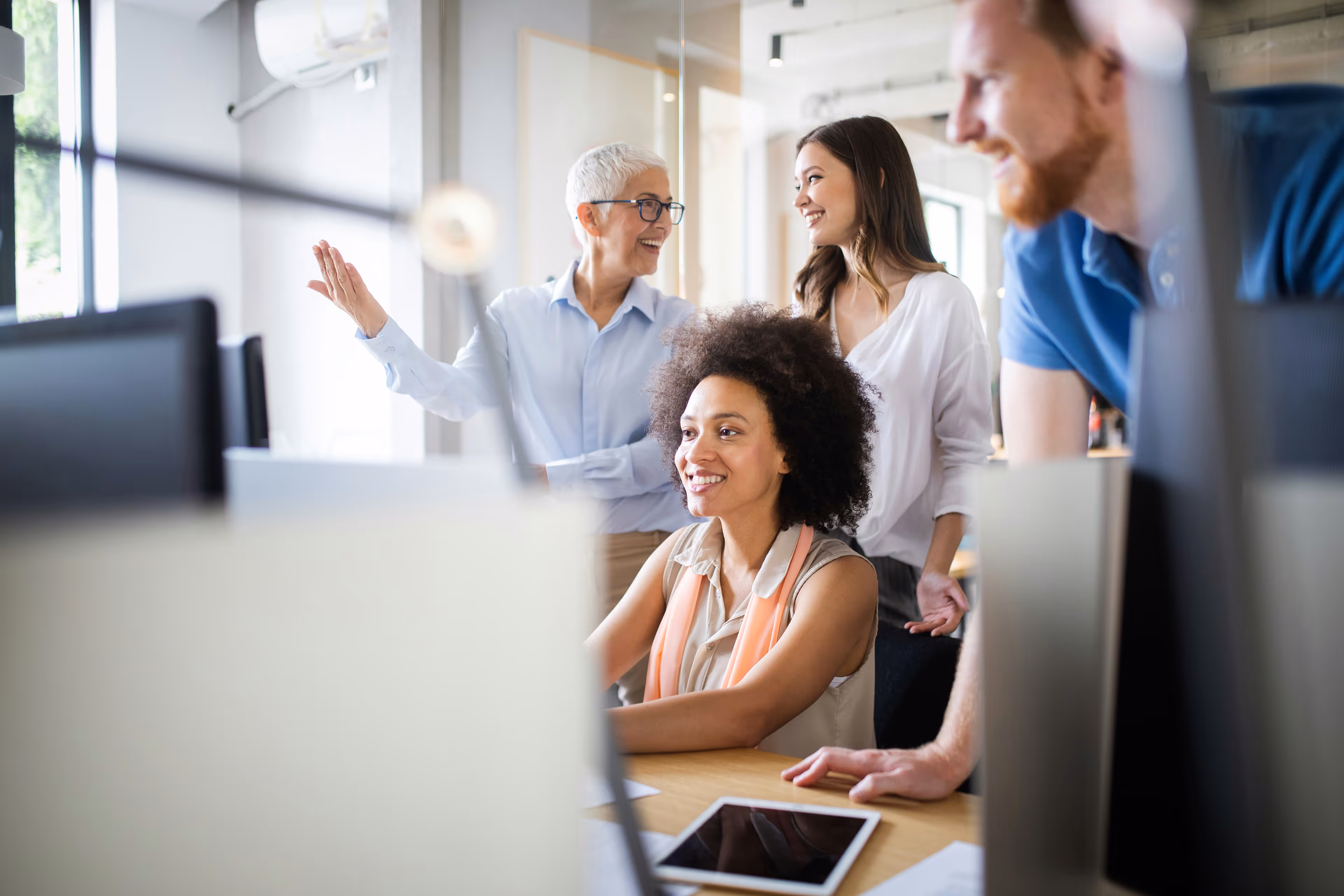 Vier Kollegen arbeiten zusammen in einem modernen Büro, glücklich und engagiert.