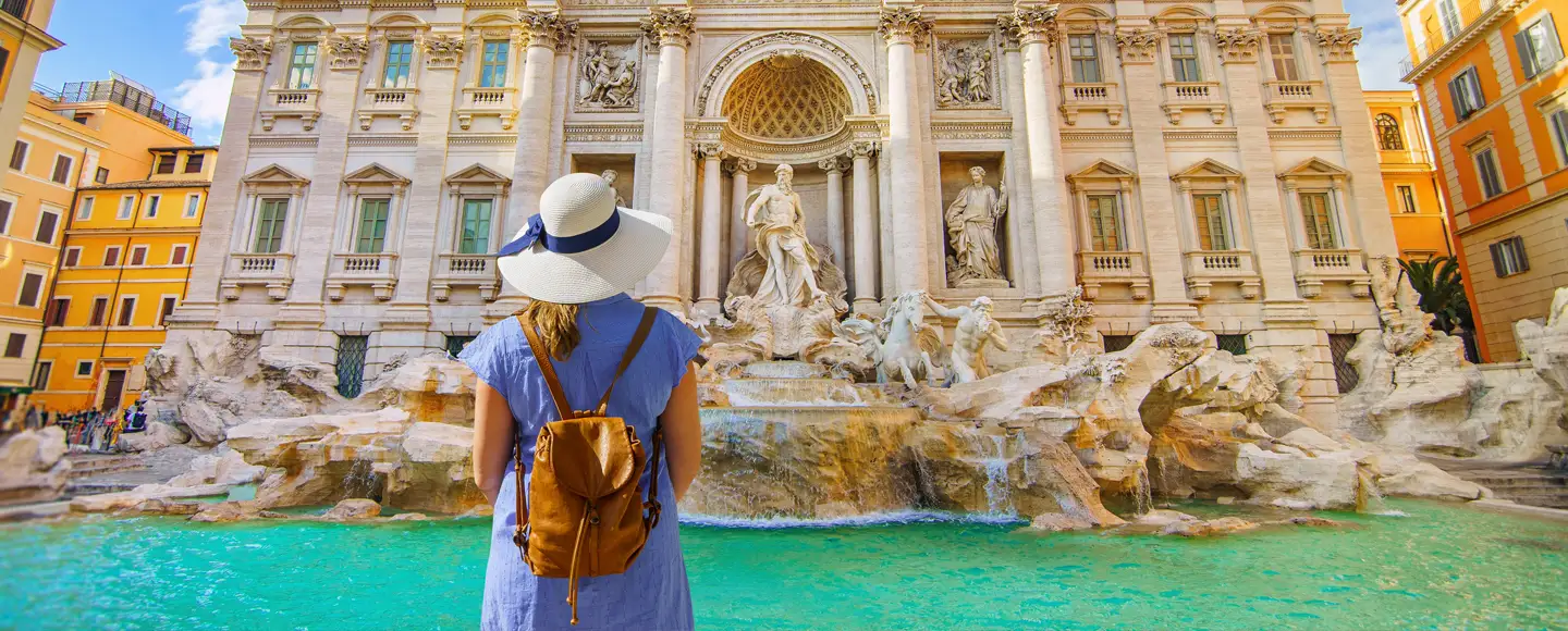 une touriste est devant la fontaine de Trevi à Rome. Elle est partie en vacances en Septembre