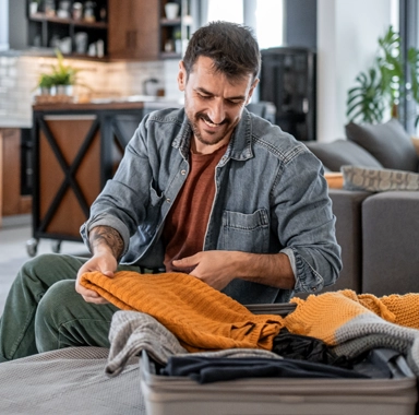 un homme prépare sa valise pour partir en vacances au mois d'avril