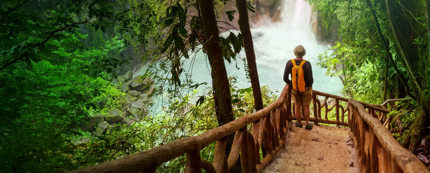 une homme observe une cascade d'eau sur un escalier en pleine jungle. il est parti en vacances en mars