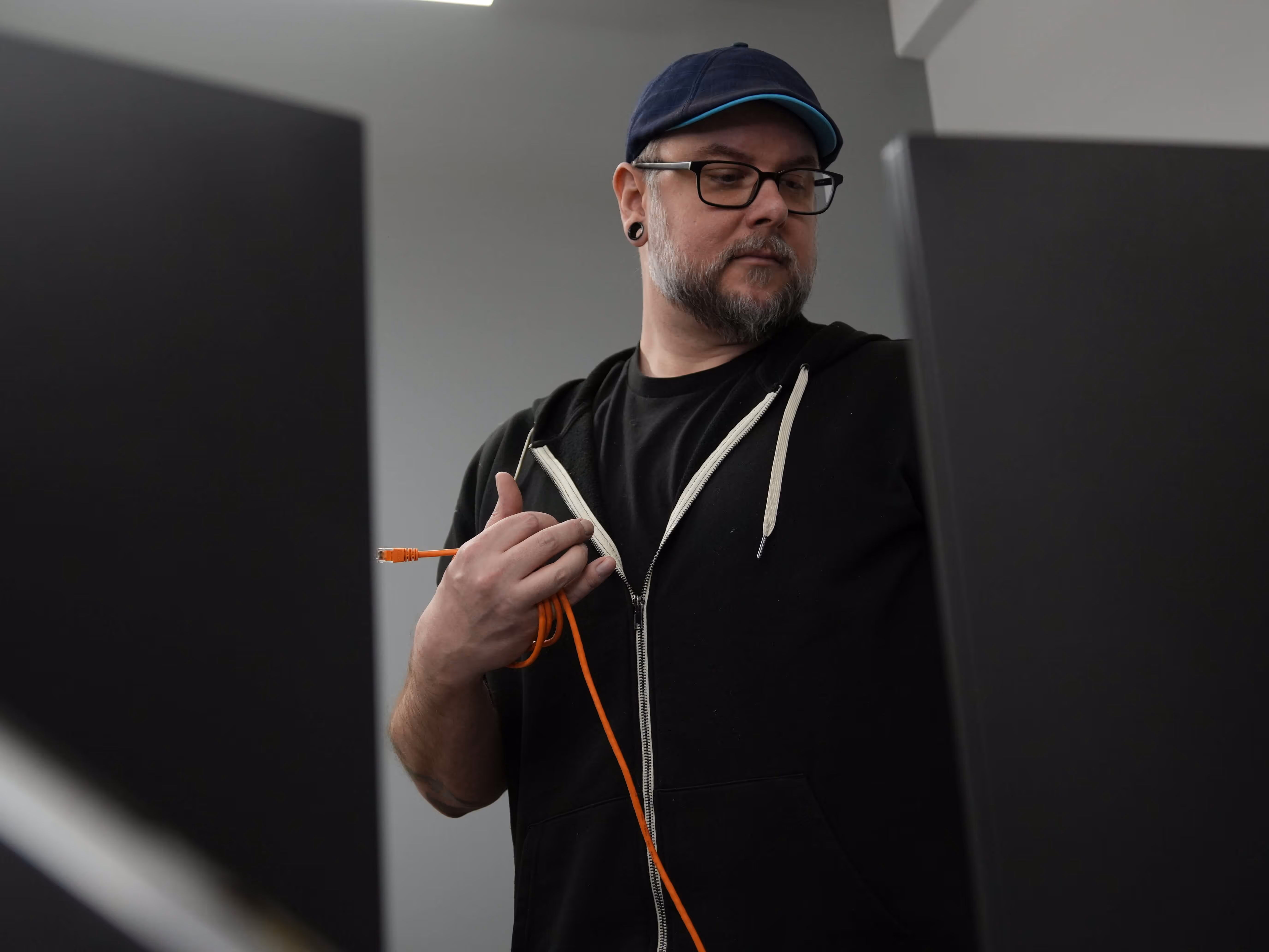 IT professional handling an orange ethernet cable in a server room.