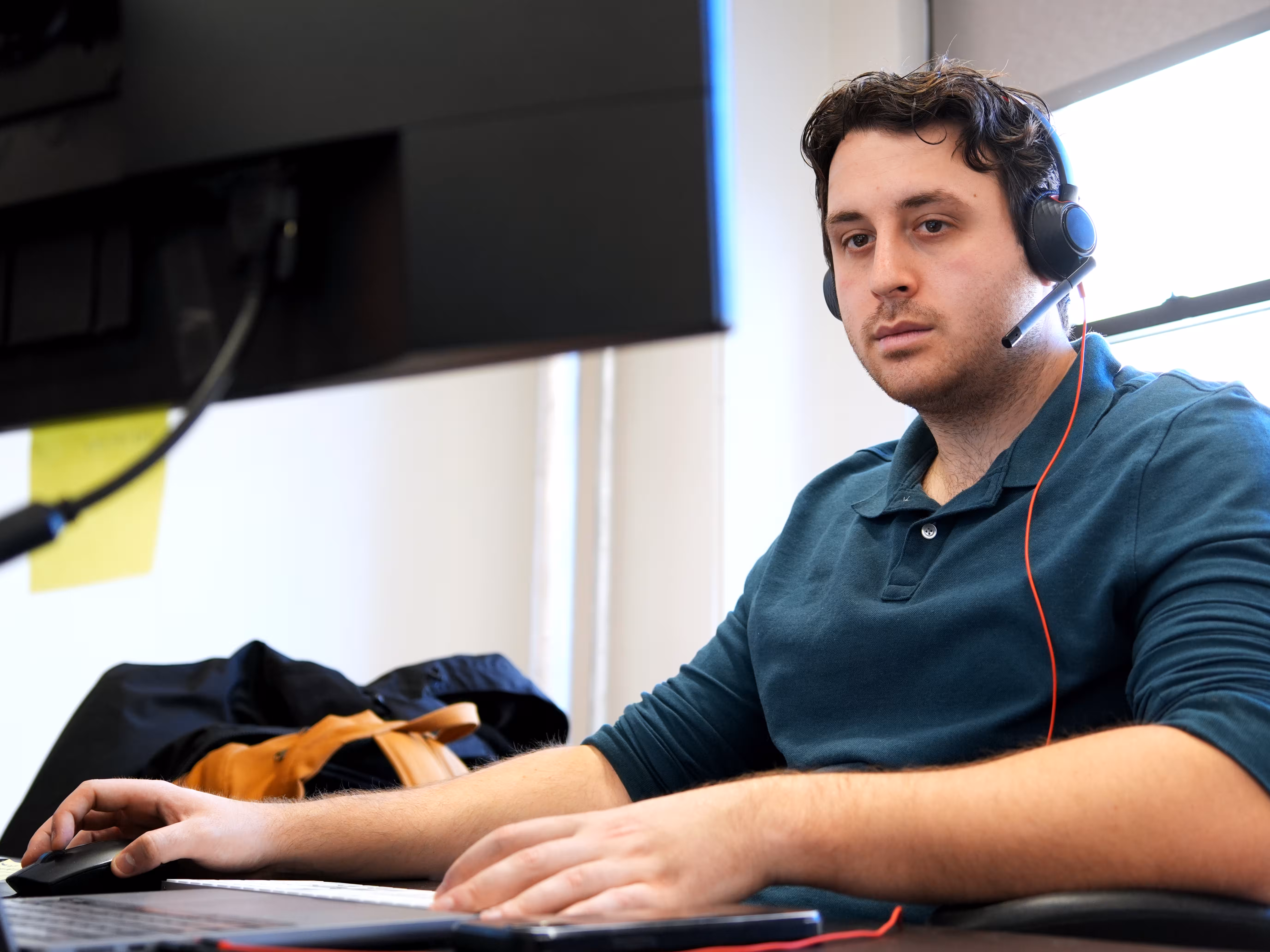 IT professional wearing a headset working at a desktop computer.