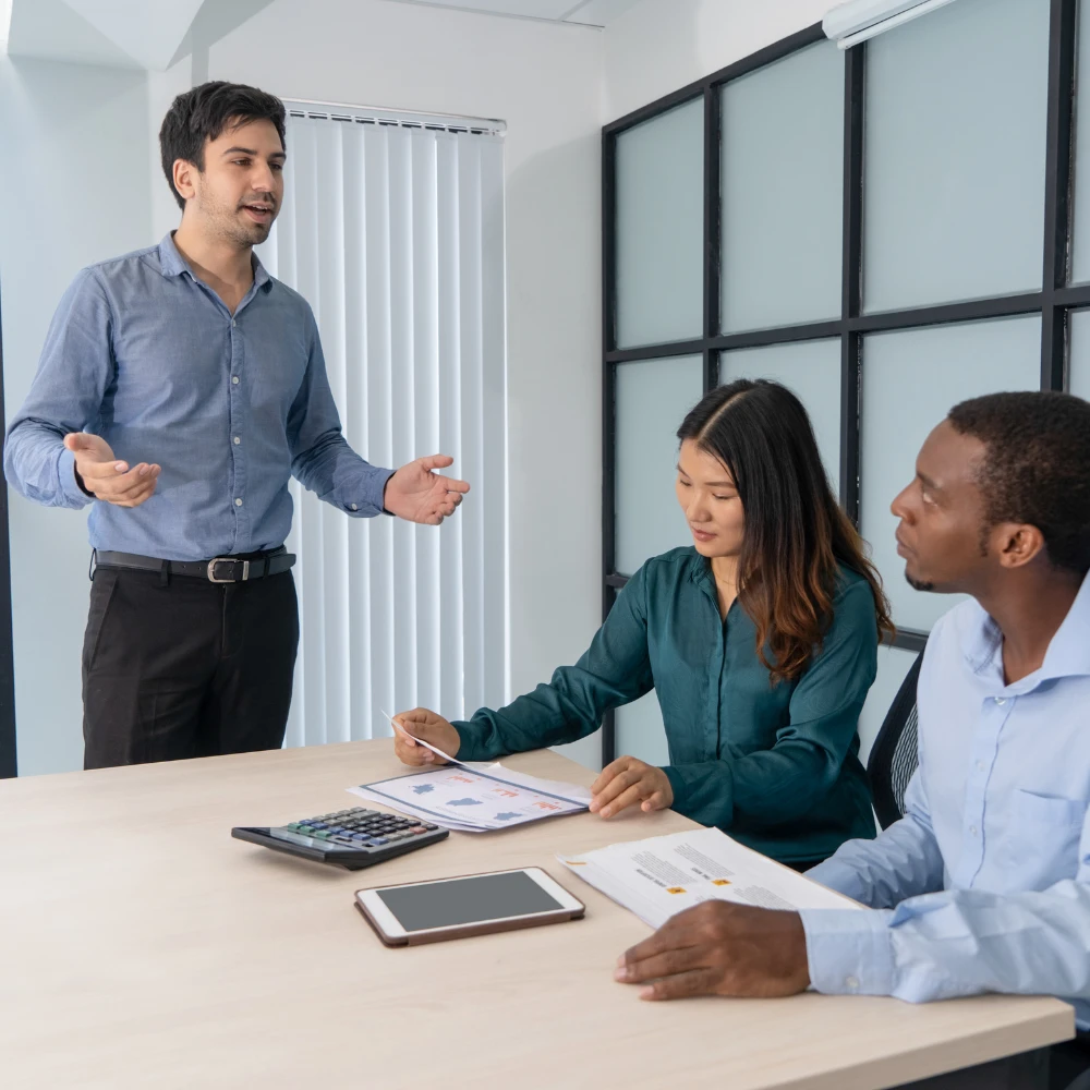 Three professionals in a meeting reviewing documents and discussing financials