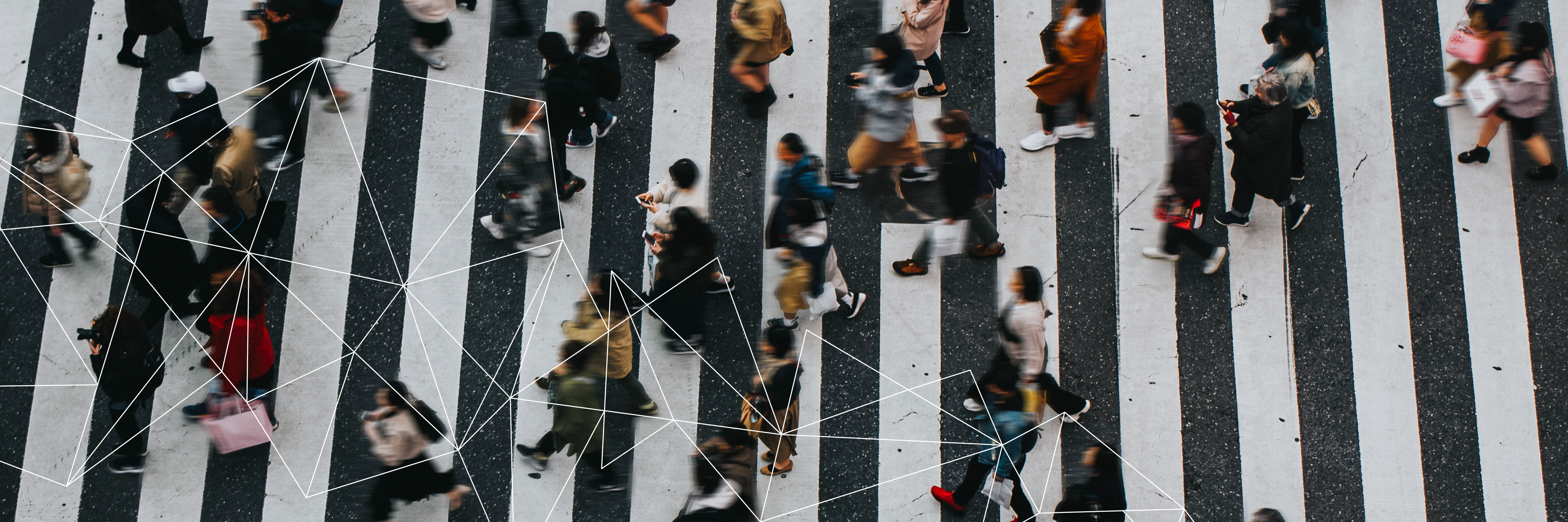 Overhead view of blurred pedestrians crossing a striped street crosswalk with connected white lines overlay.