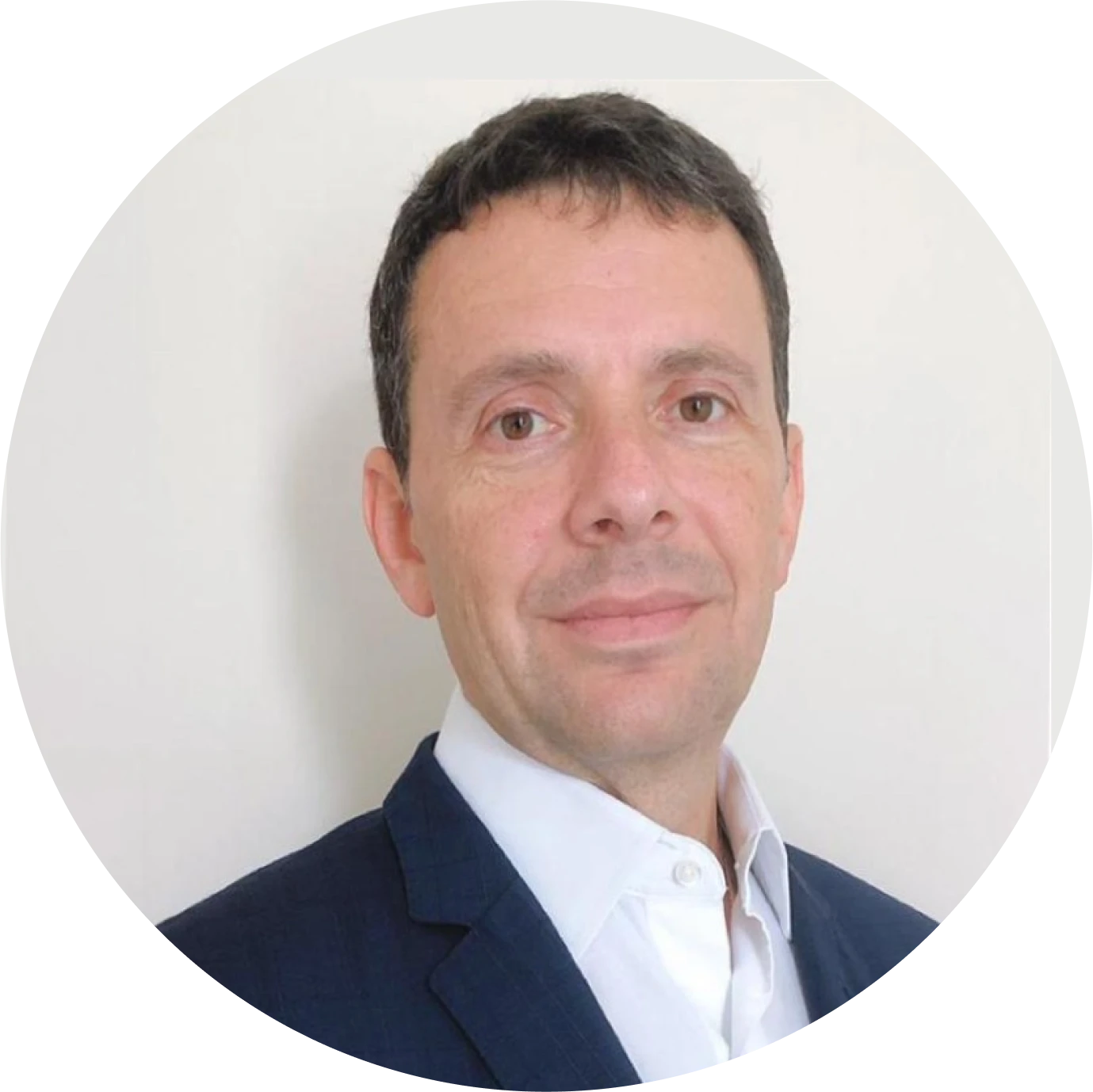 Portrait of a man with short dark hair wearing a navy suit jacket and white shirt against a plain light background.
