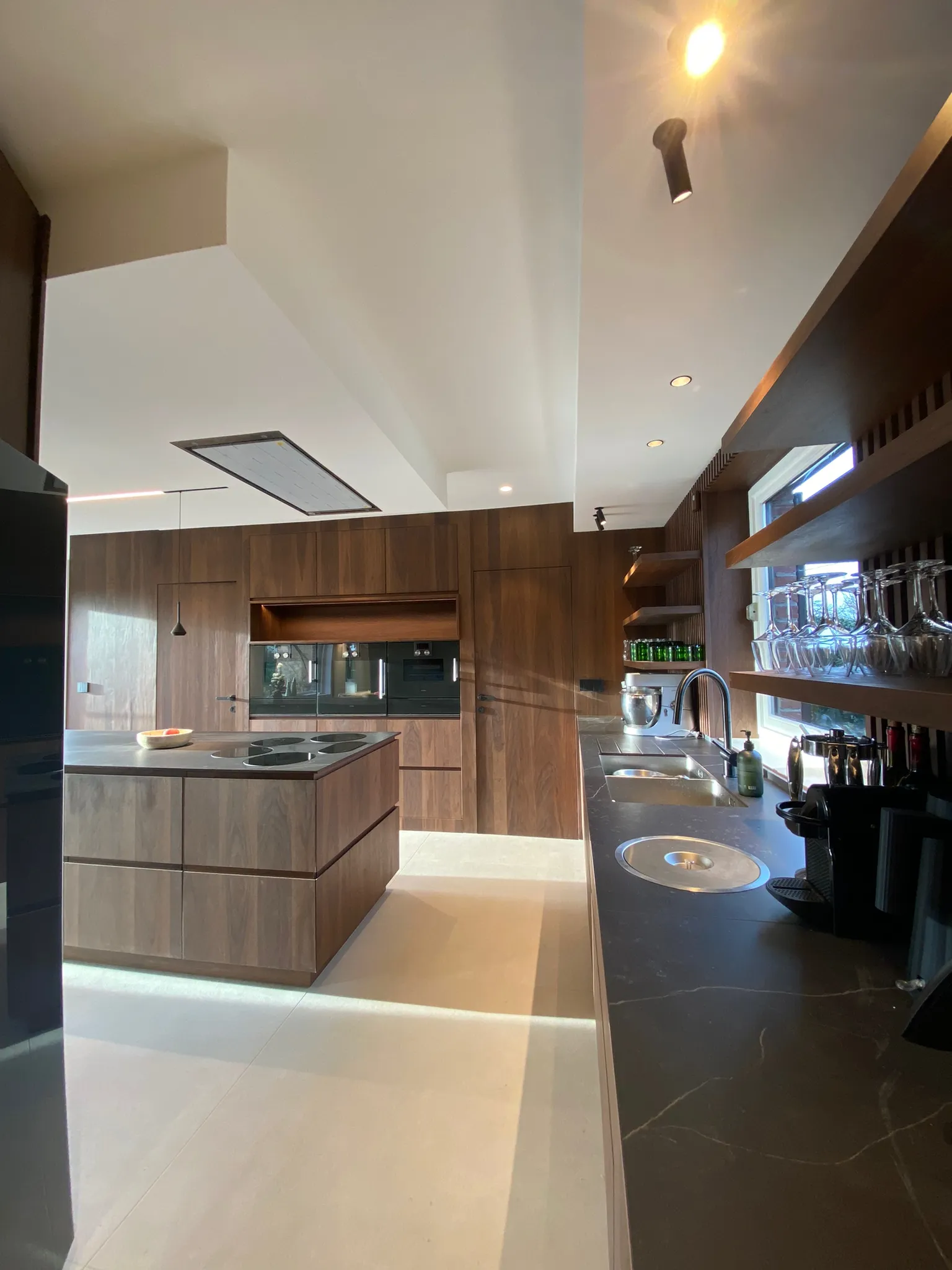 Cuisine moderne en noyer et îlot central noir mat, conception sur-mesure par un architecte d'intérieur pour une maison des années 2000