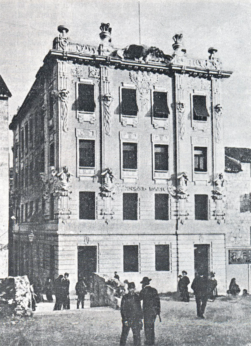 Black and white photo of an ornate Croatian House with detailed facade and several people standing and walking in front.