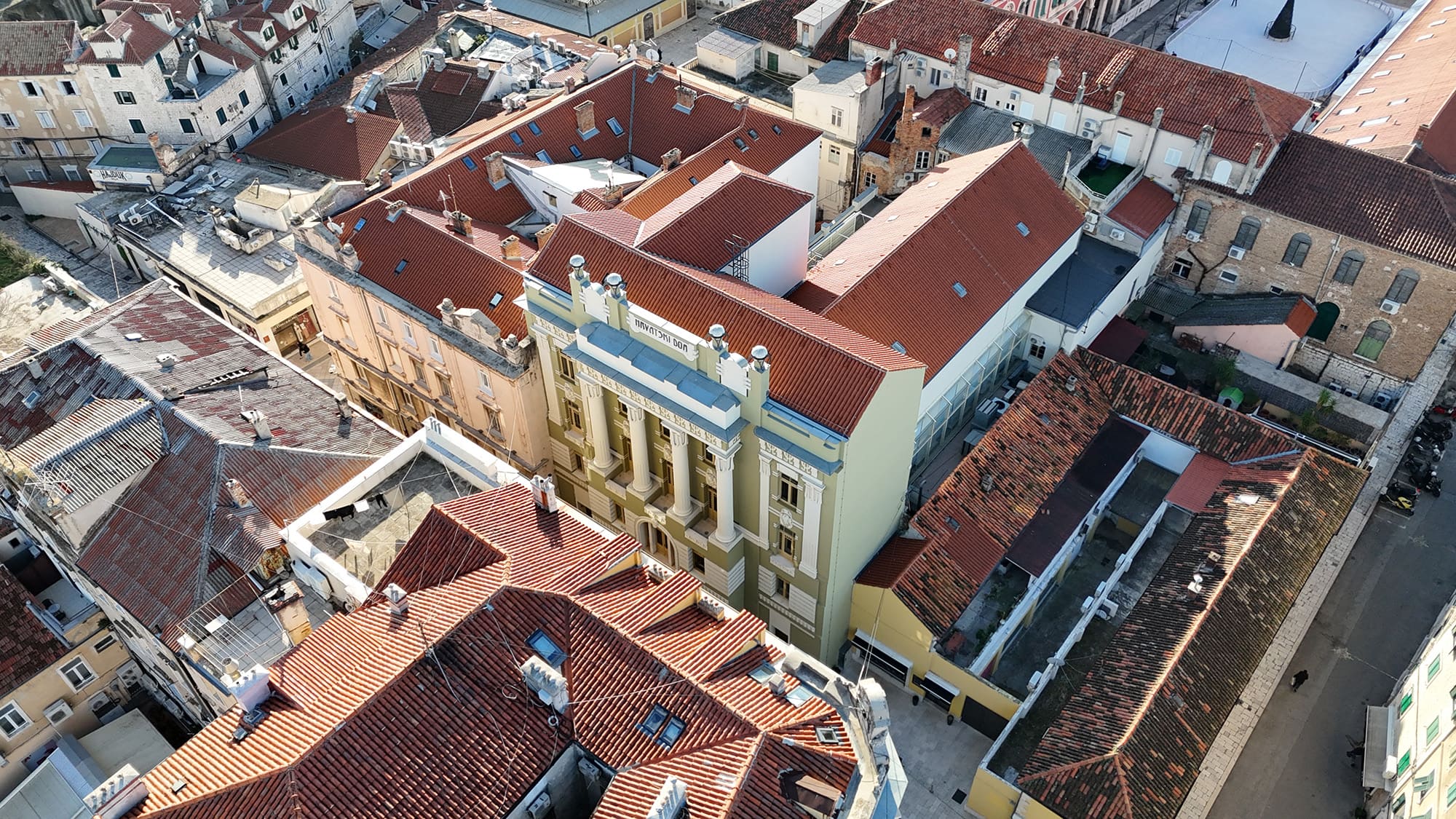 Aerial view of Croatian Home and buildings with red tile roofs closely packed together in a narrow street.
