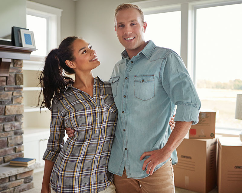 New homeowners posing in their living room.