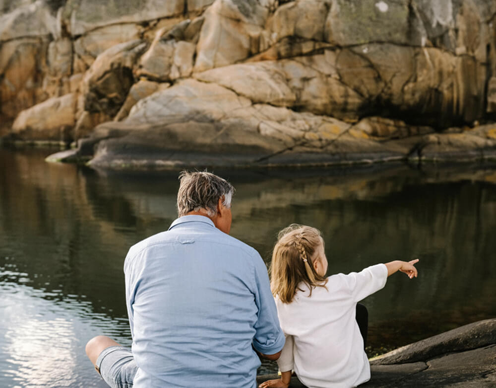 Bilde av en mann og sitt barnebarn ved fjøren