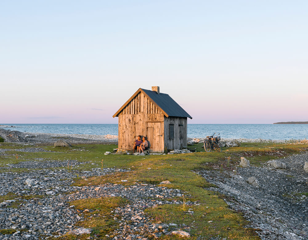 Bilde av to personer som sitter ved en hytte