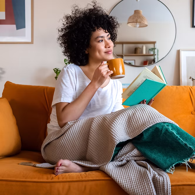 Foto einer Frau mit einer Tasse und einem Buch