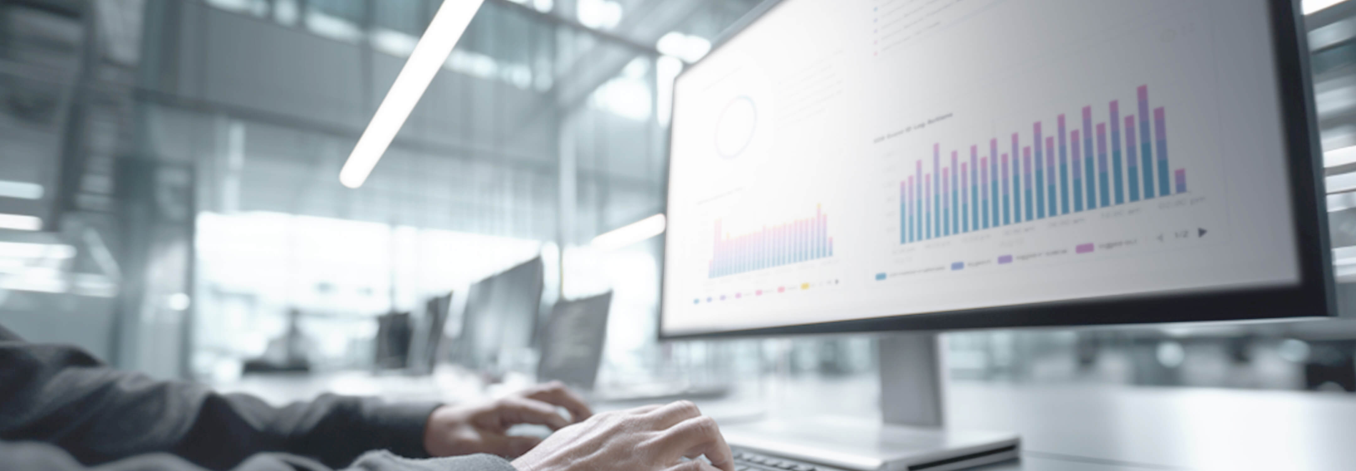Cybersecurity analyst monitoring SIEM and MXDR data visualizations on a large office monitor.
