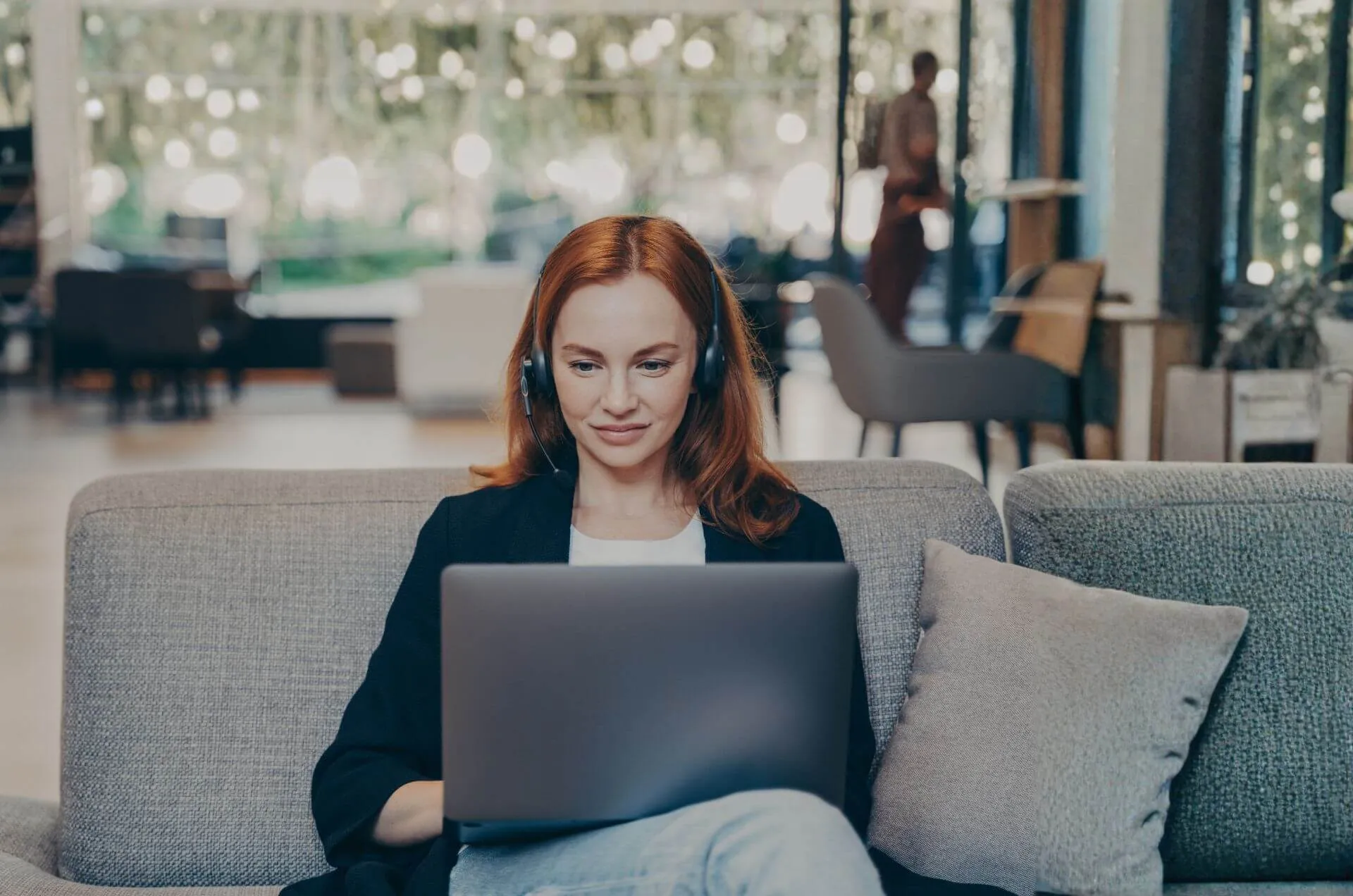 Frau sitzt während Human Design Session mit Laptop auf einer Couch im Büro