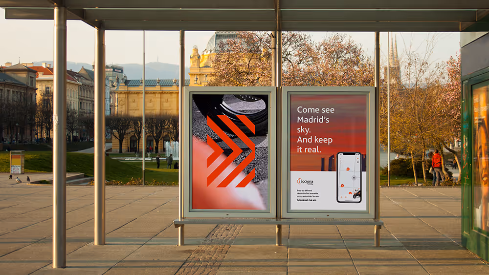 Mupis en una parada de autobús con anuncios de Acciona Mobility mostrando un mensaje para explorar Madrid y descargar una aplicación.