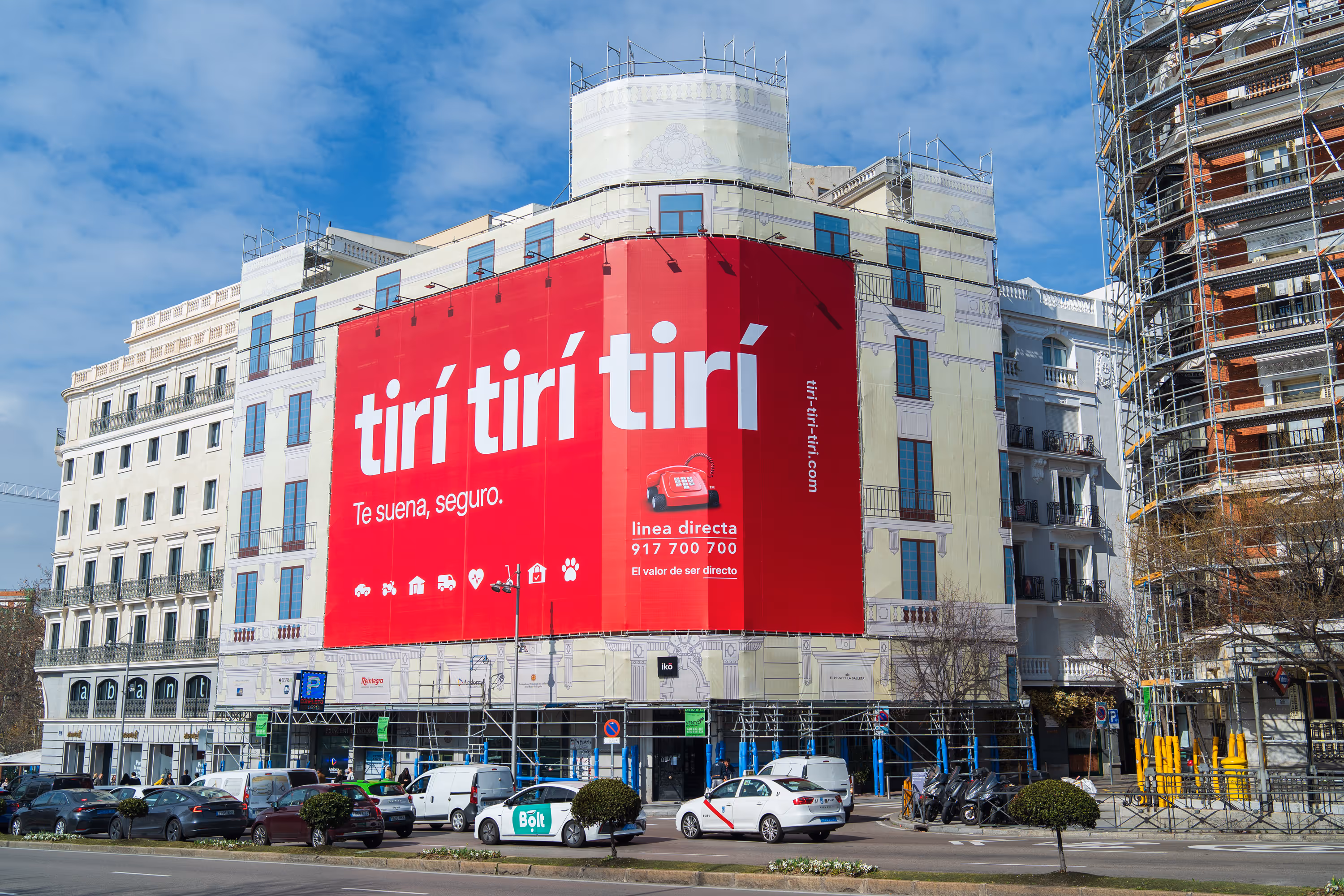 Gran cartel rojo en edificio con texto blanco que promociona seguros de Línea Directa con número de teléfono y sitio web.