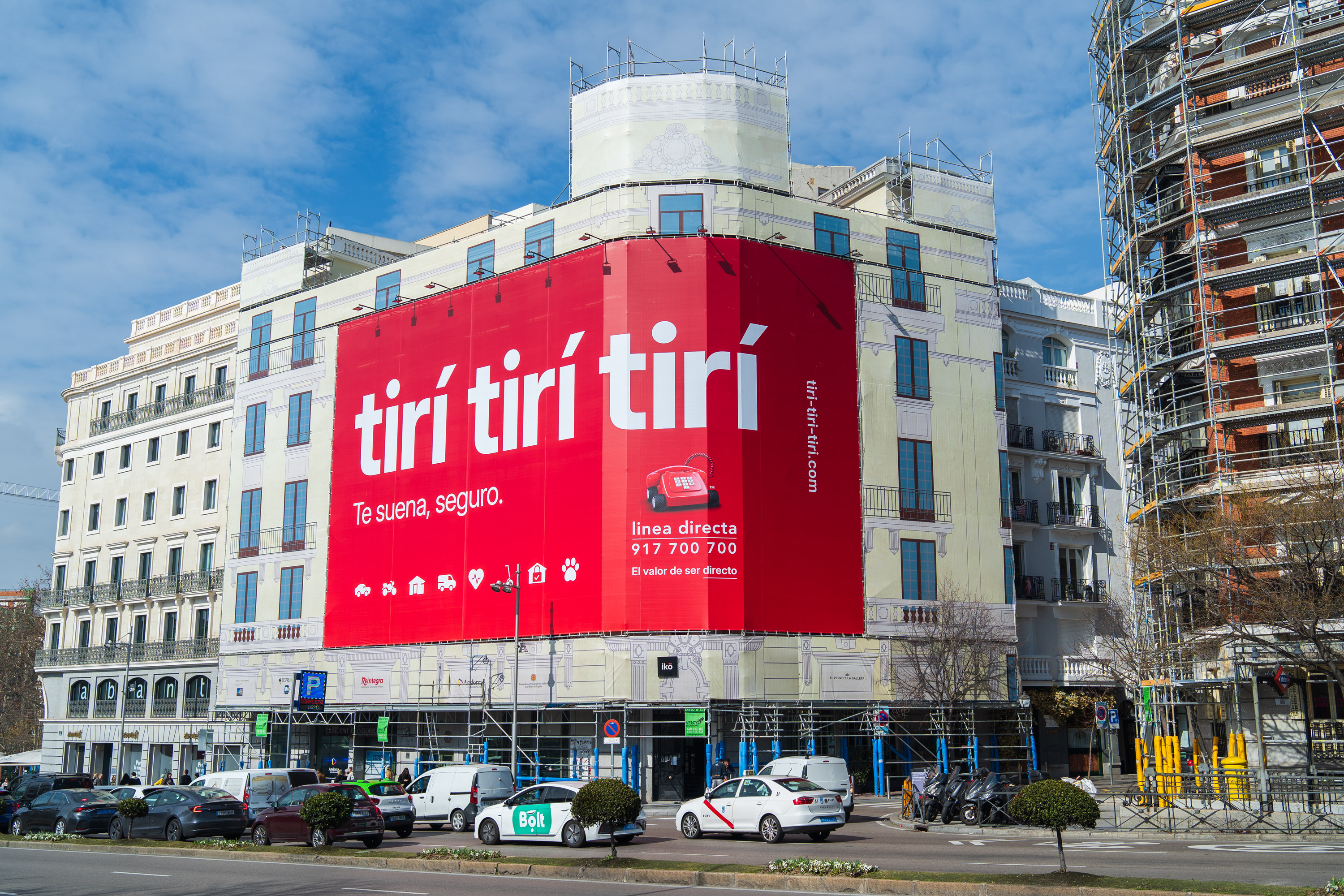 Gran cartel rojo en edificio con texto blanco que promociona seguros de Línea Directa con número de teléfono y sitio web.