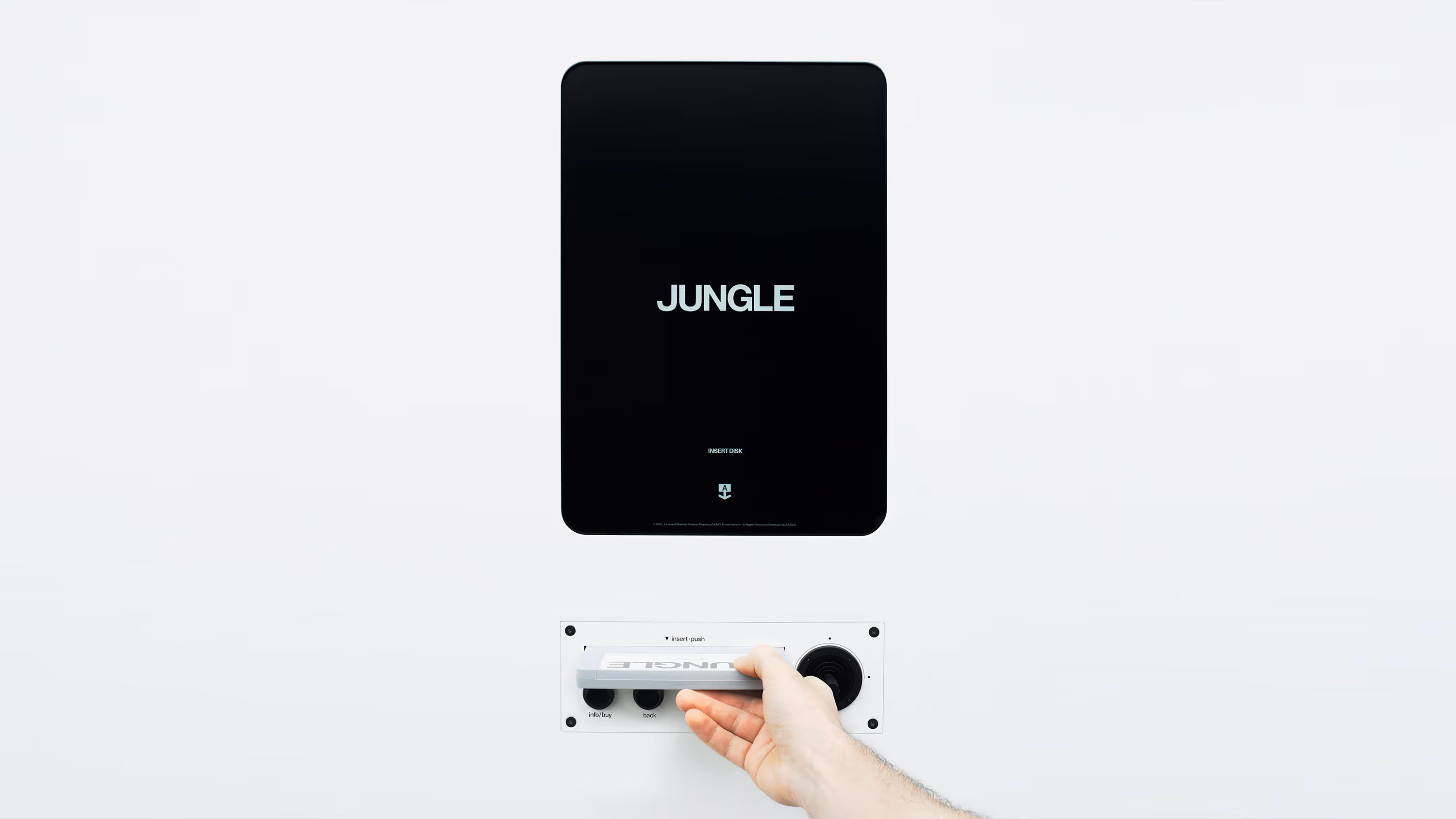 Una mano insertando un disco en una máquina blanca con una pantalla que muestra la palabra JUNGLA.