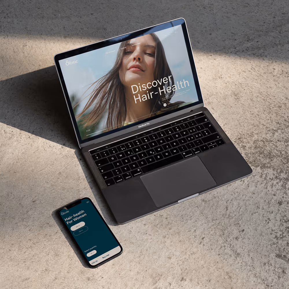 Portátil MacBook Pro y teléfono móvil sobre superficie de cemento mostrando contenido sobre salud capilar para mujeres.