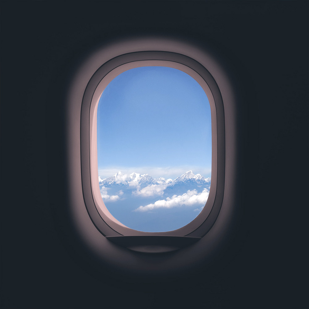 Vista de montañas nevadas y nubes desde la ventana de un avión.