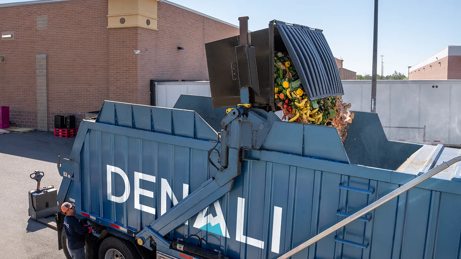 Blue Denali truck picking up dumpster full of food to be recycled