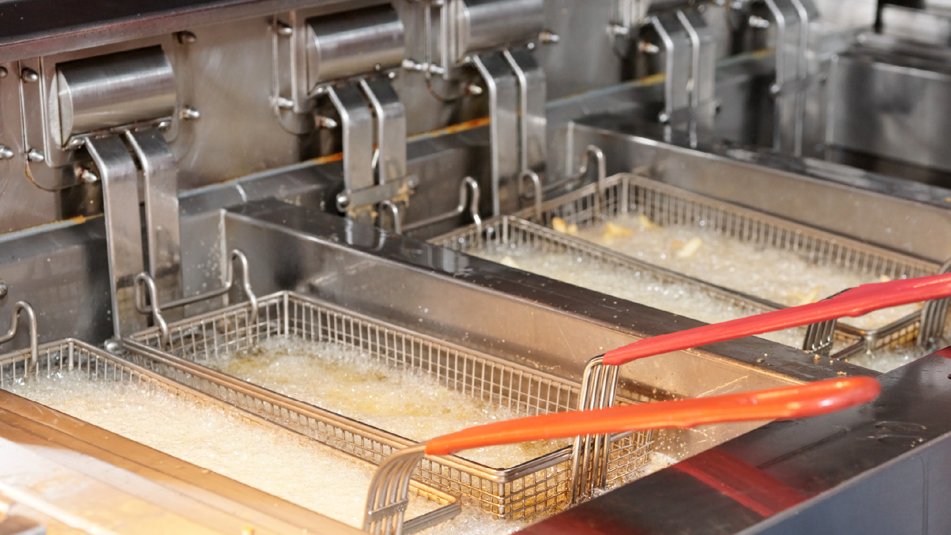 Photograph of multiple baskets in an oil-filled commercial deep fryer.