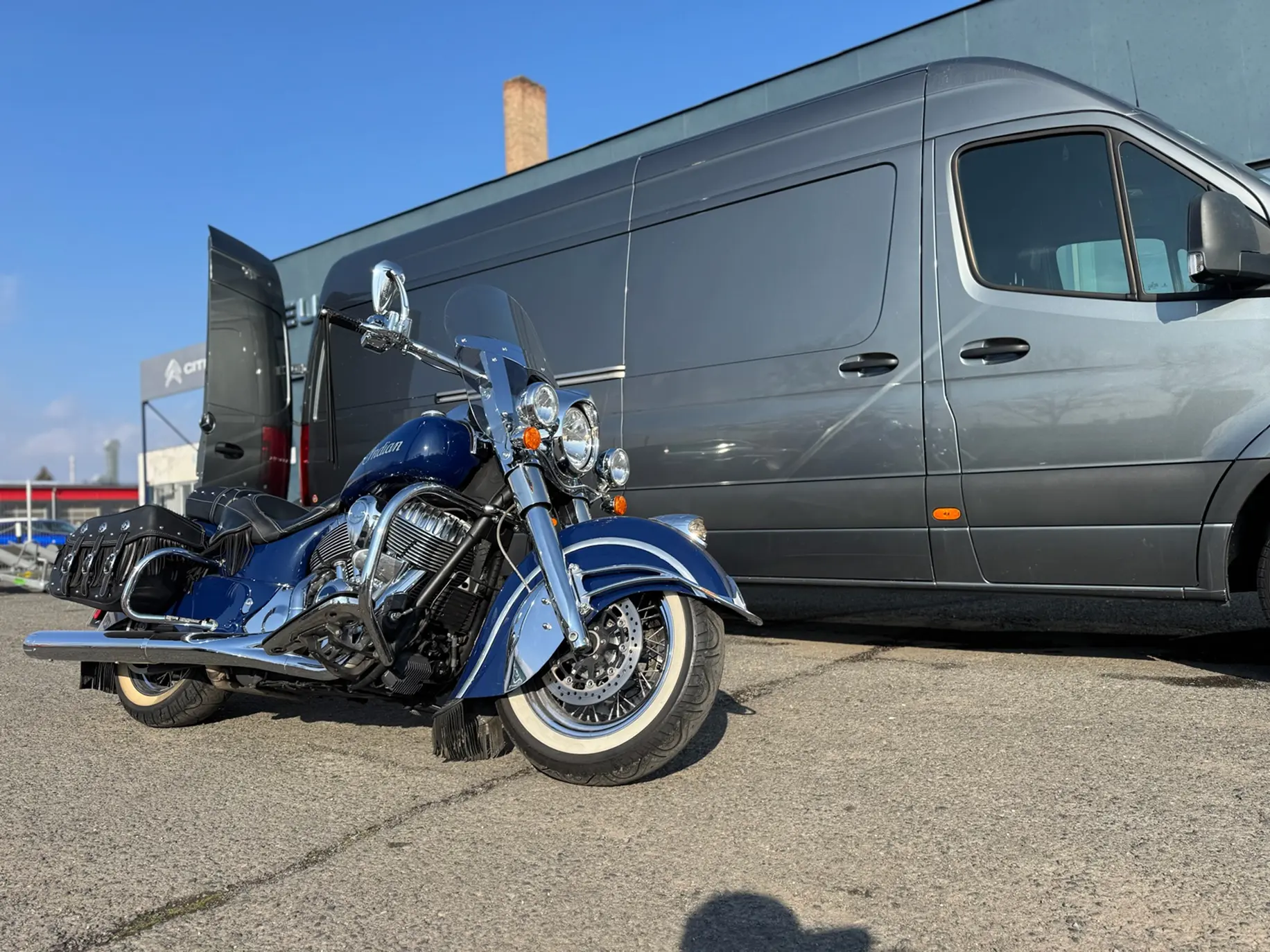 A beautiful blue motorcycle in great conditions in front of a van.