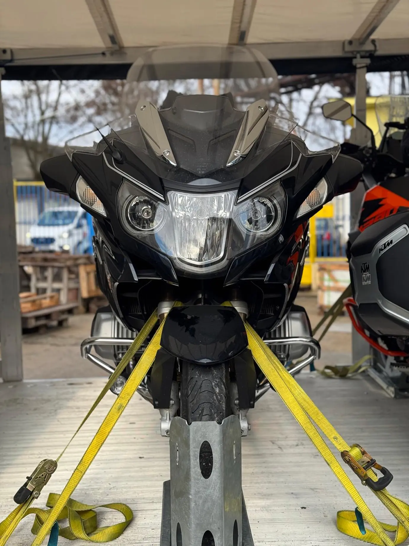 A black motorcycle securely fastened inside an enclosed trailer, with focus on the front.