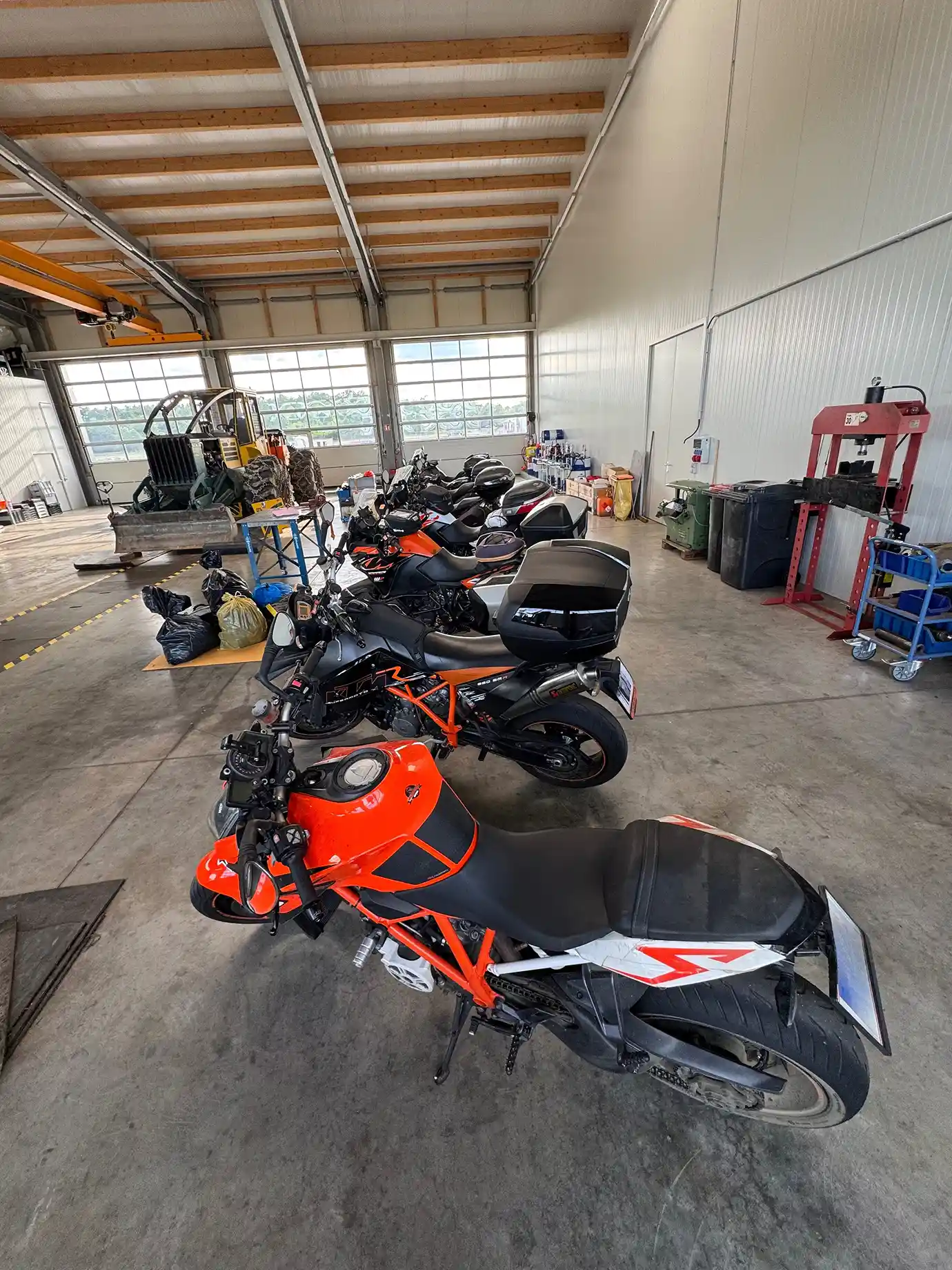 Eight motorcycles parked side by side inside a warehouse.
