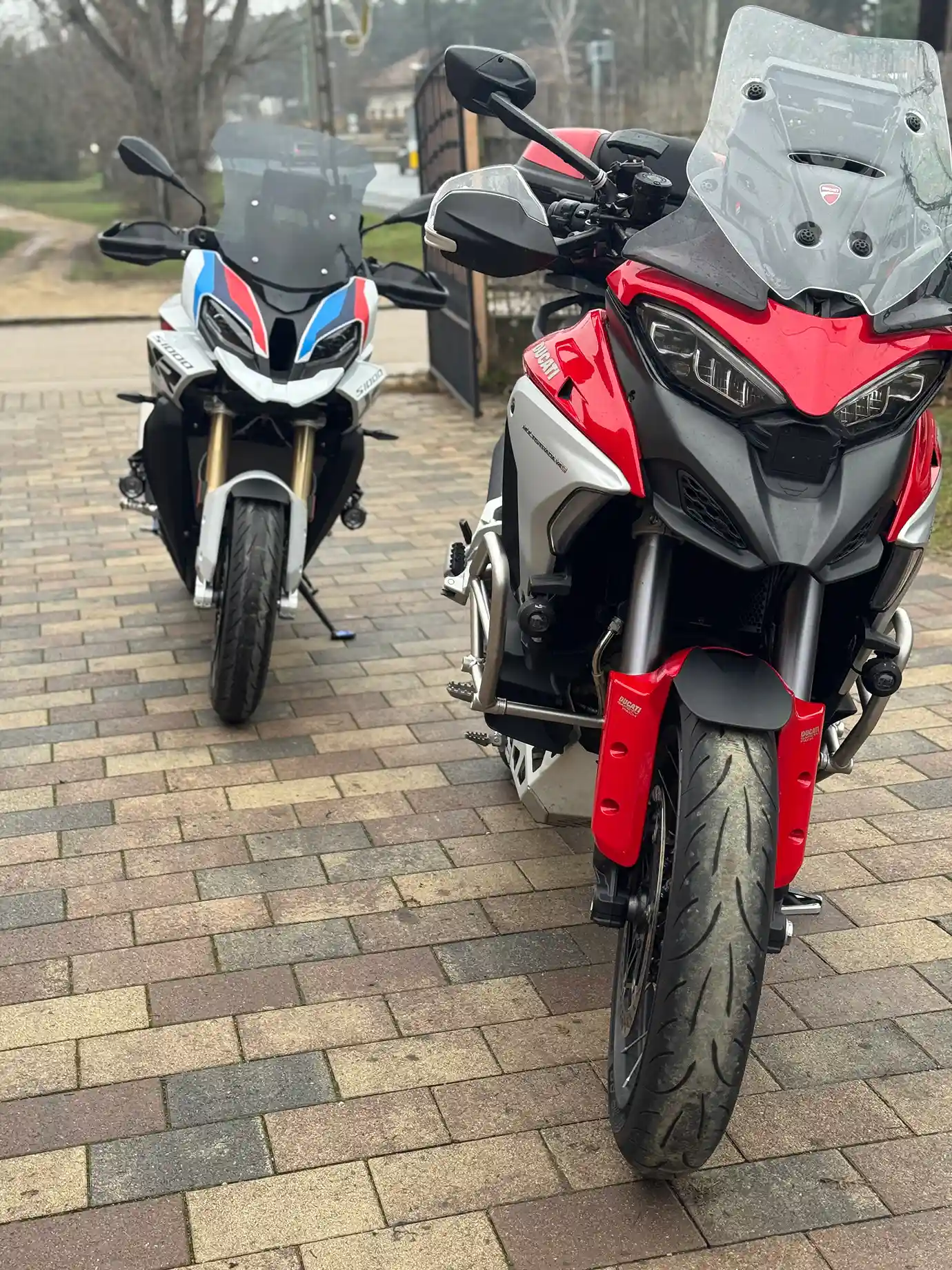 Two street motorcycles parked on the sidewalk.