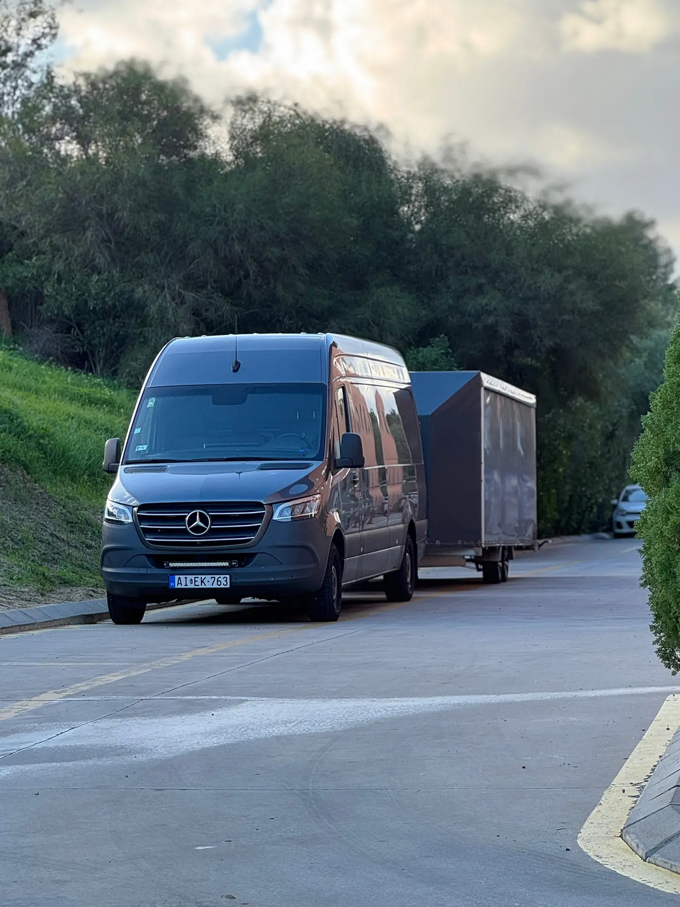 Grey van and enclosed trailer parked on the roadside.