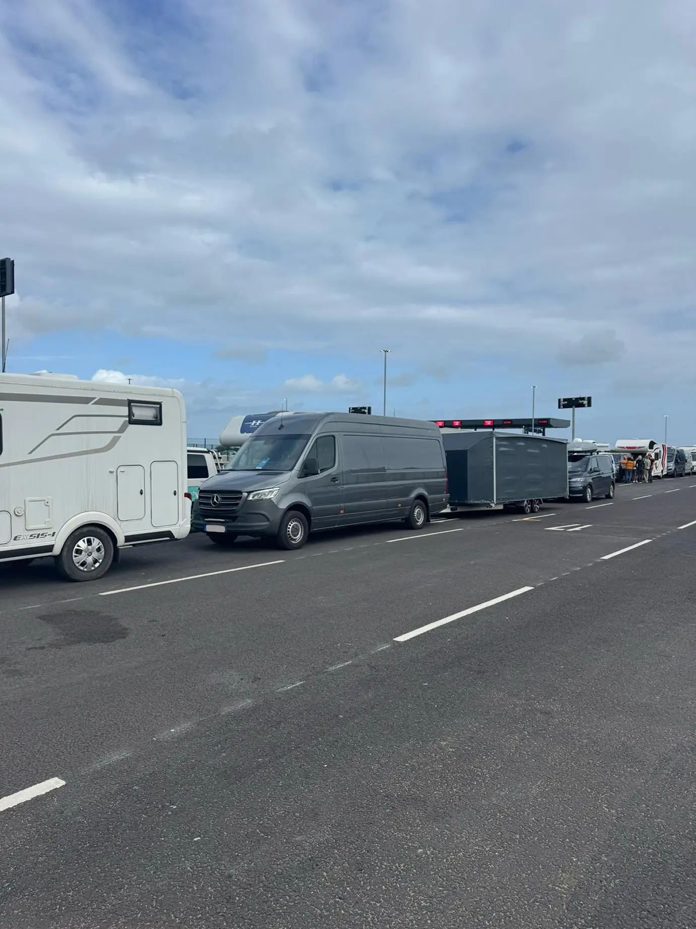 A van and an enclosed trailer waiting in a line of vehicles.
